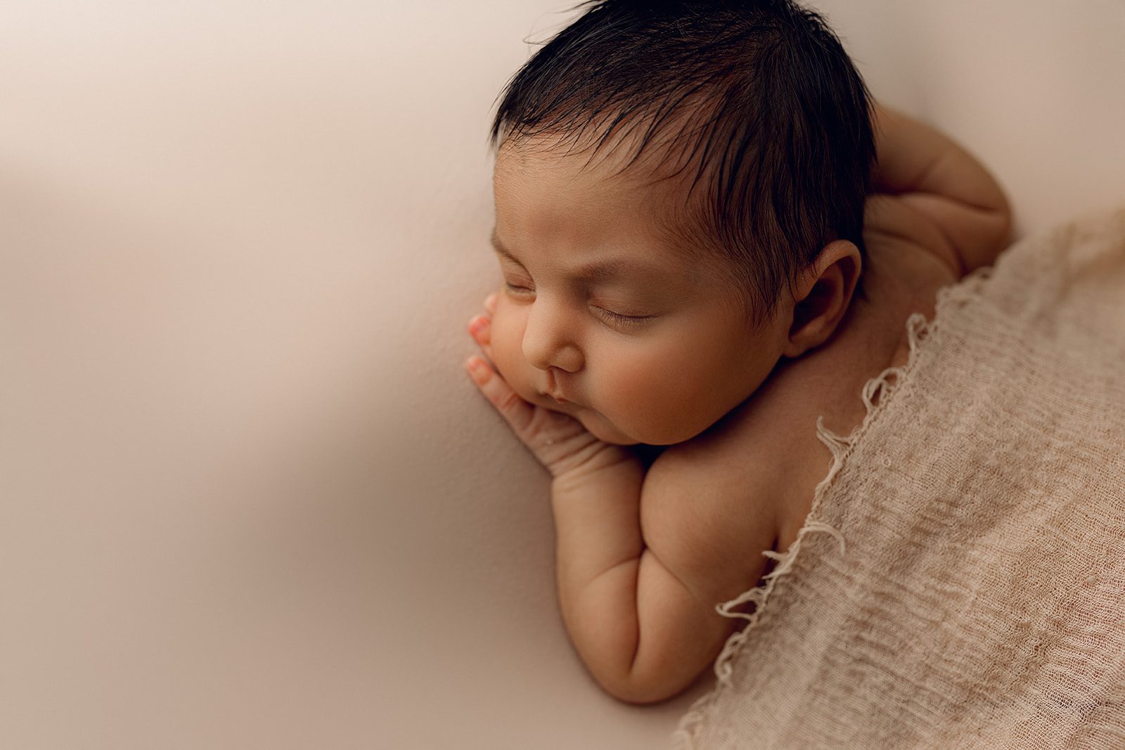 A newborn baby sleeps on its cheek in a studio with help from Joyful Birth